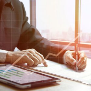 a business person looking at statistics on paper and a tablet with a rising chart overlay