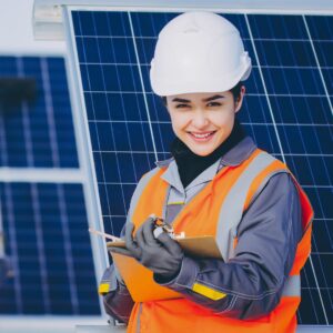 a woman in safety gear with a clipboard in front of solar panels