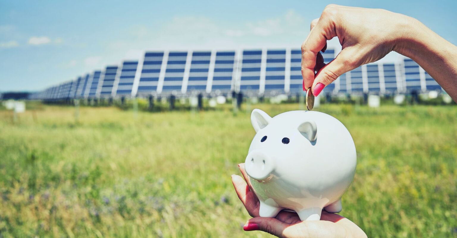 a person putting coins in a piggy bank in front of solar panels