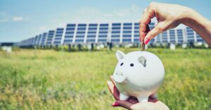a person putting coins in a piggy bank in front of solar panels