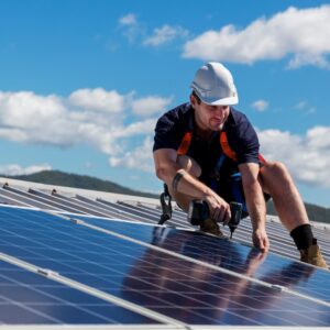 a worker in safety gear attending to solar panels