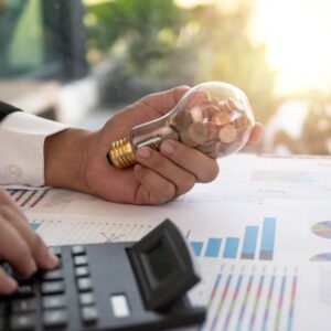 a person looking at statistics while holding a lightbulb full of coins