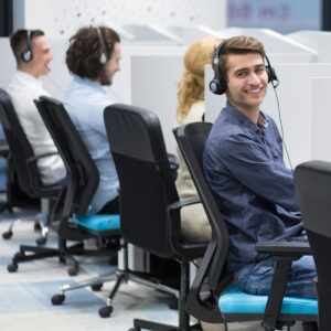 a worker smiling in an office space with many other workers around him