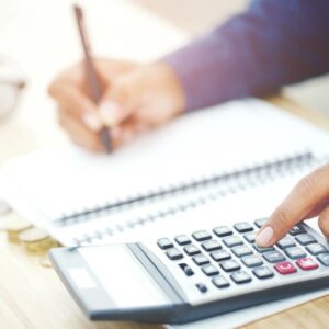 Person using a calculator and writing in a notebook