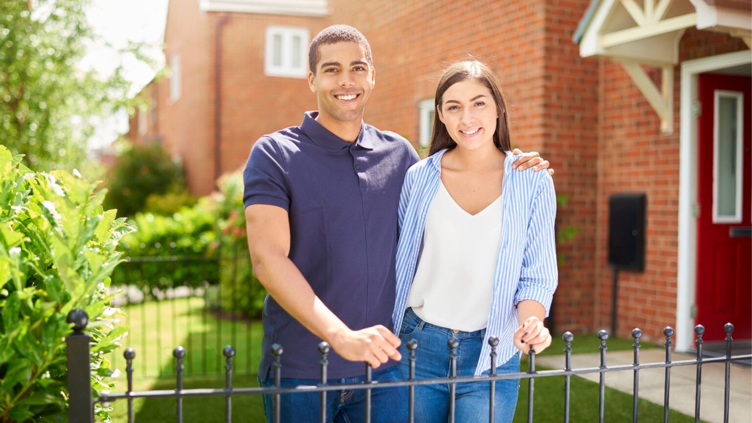 Couple standing in the front yard of their home smiling at the camera