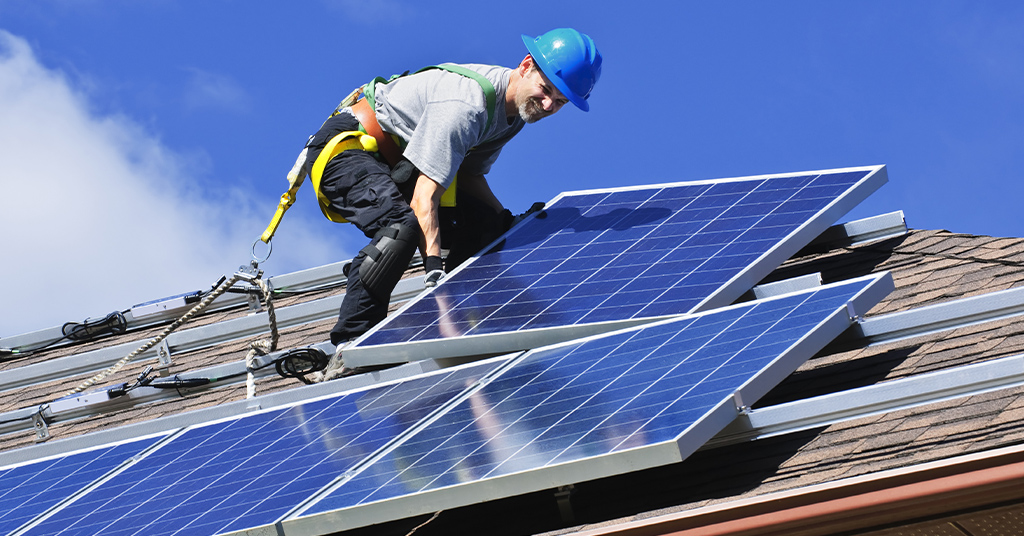 a professional in safety gear installing solar panels on a roof