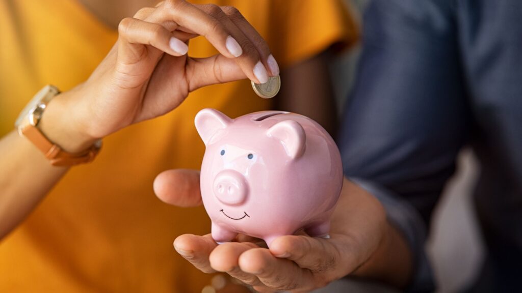 a couple adding money to a piggy bank